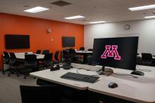 A computer monitor and keyboard are seen in the foreground, in the background there are 2 active learning stations next to an orange colored wall.